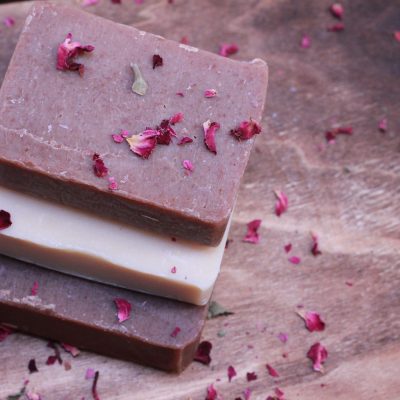 3 bars of soap stacked vertically with rose petals sprinkled on top and spread around