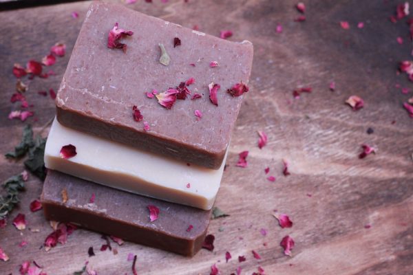 3 bars of soap stacked vertically with rose petals sprinkled on top and spread around